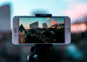 Image shows a mobile phone in video-mode on a tripod. Image is referring to why video is so hyped based on it being such an accessible medium through everyone's mobile phone nowadays.